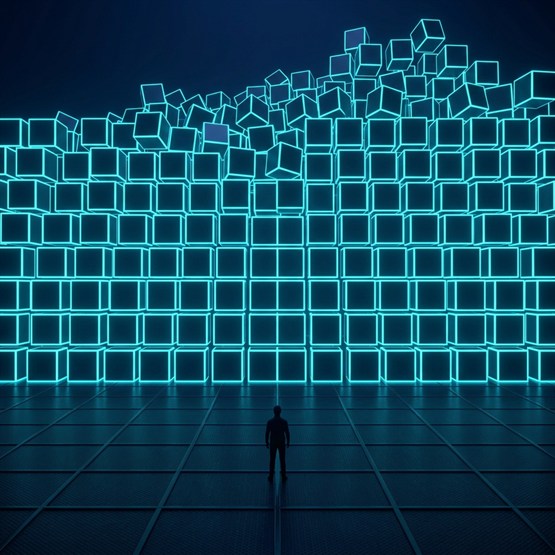A lone figure seen from behind at the base of a towering wall of glowing cubes rising and piling higher against the dark